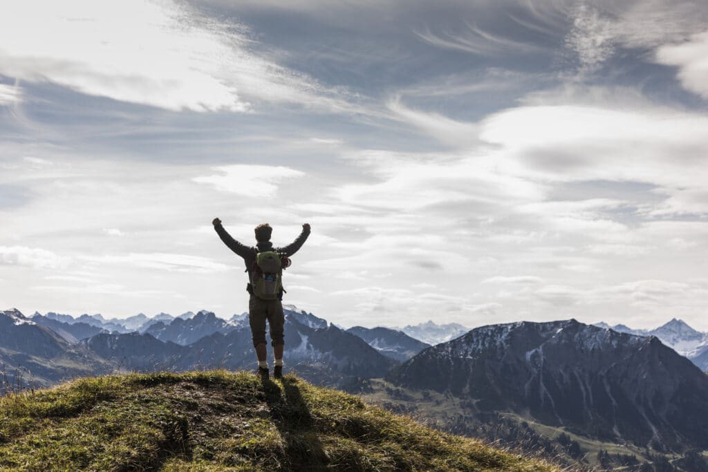 Austria, Tyrol, young man standing in mountainscape cheering