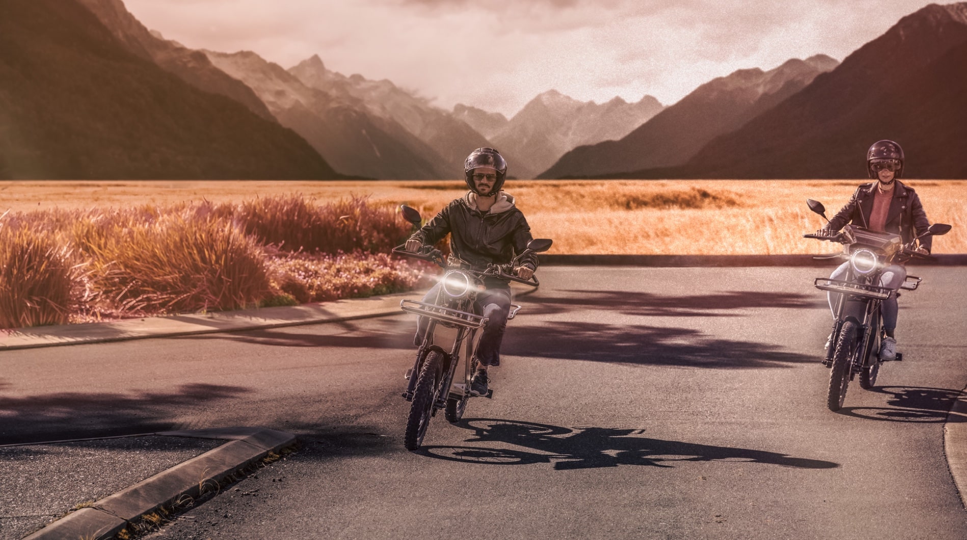 Two people riding electric bikes on a road in New Zealand.