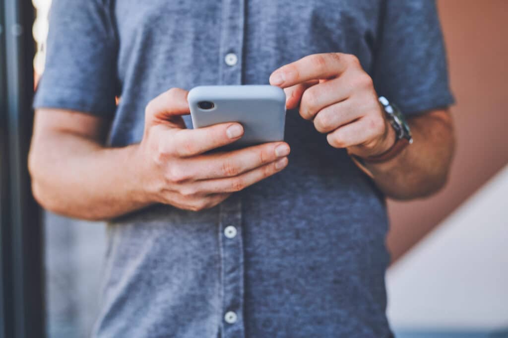Closeup of man hands on a phone browsing on social media.