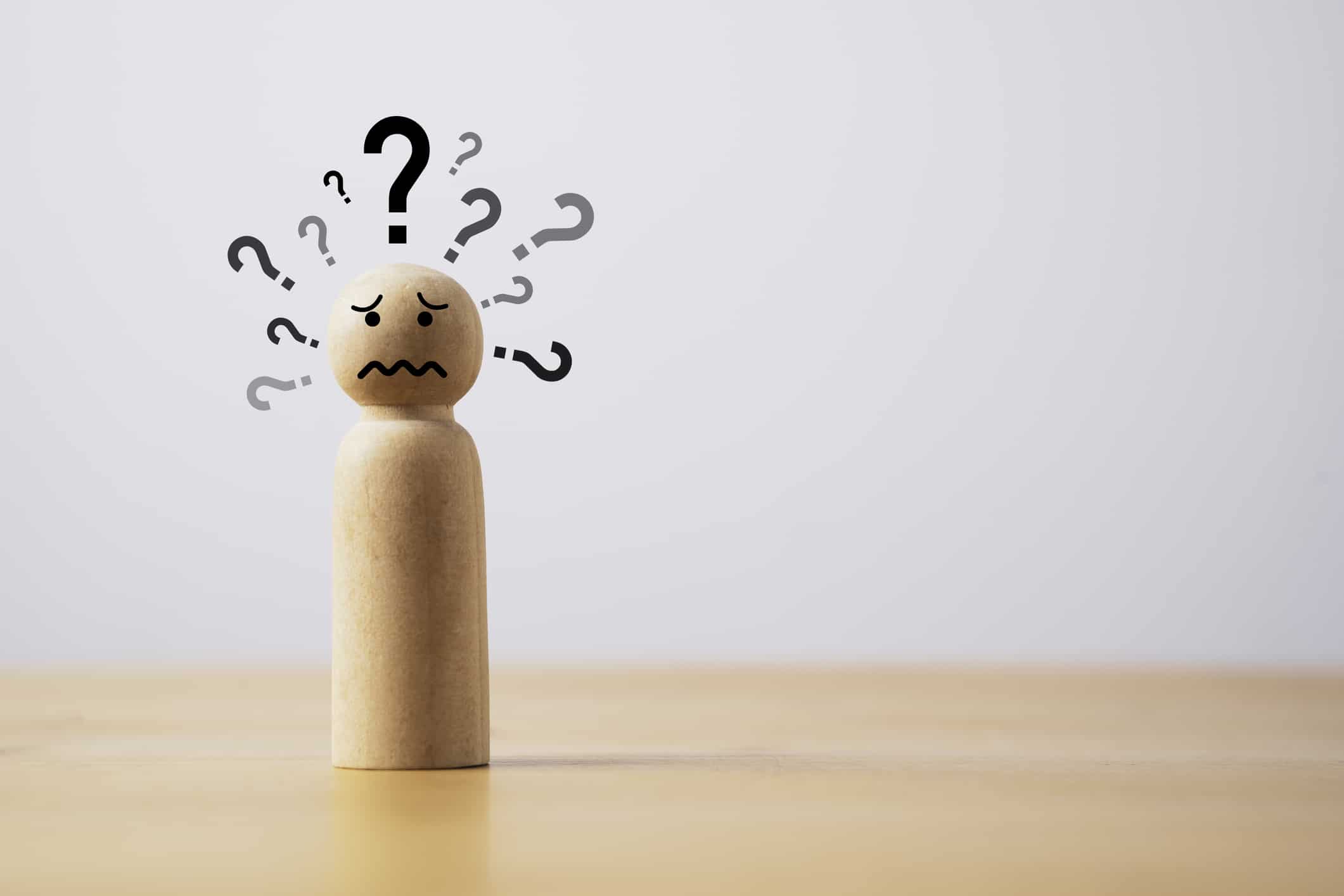 Wooden figure with many questions mark and copy space for doubt suspicion and doodle concept.